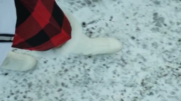 雪の中を歩く白いブーツの女の子の足 人間の足は痕跡を残して雪の上にあり 去っていく 高品質の4K映像 — ストック動画