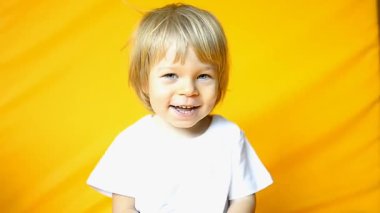 Çocuk 2 yaşında, sarı saçlı, beyaz tişörtlü ve sarı pantolonlu. Duygular. Çocukluk ve aile kavramı. Bebek manzarası sarı izole arkaplan