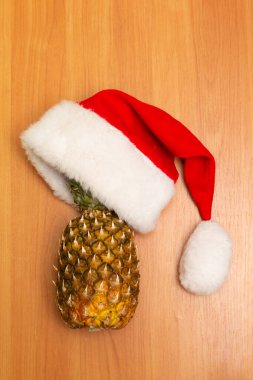 Yeni yıl kompozisyonu ahşap bir arka planda. Yeni yıl şapkası, ananas ve mandalina. Noel Baba şapkası. Noel konsepti.