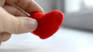 Kırmızı kalp kadınların elinde gri arka planda. Hayırseverlik, sevgi, bağış ve yardım eli kavramı. Uluslararası kardiyoloji günü. Bir kadın erkeğin ellerine kırmızı bir kalp verir..