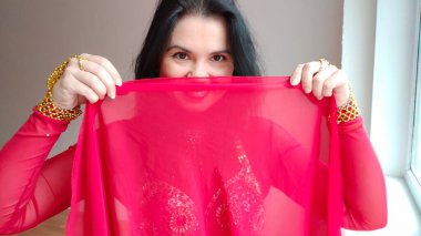 Kırmızı elbiseli bir dansçı kırmızı bir şalla dans ediyor. Beyaz arka planda doğulu bir dans. Metin için boş alan. Pankart. Profesyonel bir dansçı oryantal göbek dansı yapar. Kırmızı elbiseli seksi kadın.