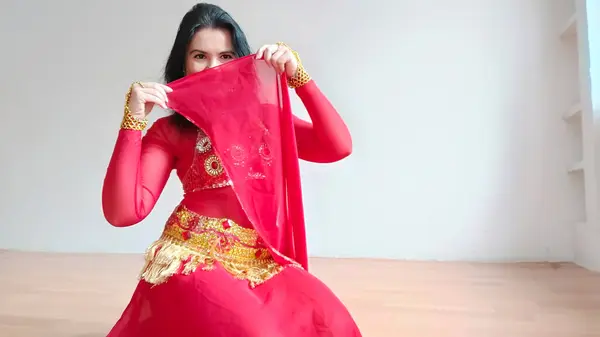A dancer in a red suit is dancing with a red shawl an oriental dance on a white background. Free space for text. Banner. A professional dancer dances oriental belly dance. Sexy woman in red dress