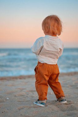 Denizin kenarında beyaz bir gömlek giyen mutlu çocuk deniz kenarına gidiyor. Mesaj için yer. Uzayı kopyala Kumsala giden mutlu çocuk dışarıda eğleniyor. Yaz tatili ve sağlıklı yaşam tarzı