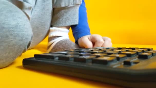 小さな子供は黄色の背景にある電卓で計算しています 子供の指のボタンを押して 自宅で数学を勉強することを計算します 子供は計算機を使って算術計算をする 高品質 — ストック動画