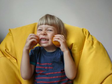 Küçük çocuk elinde domateslerle oynuyor ve gri arka planda onlarla eğleniyor. Çocuk ellerinde sebze ve domates tutuyor. Yüksek kalite fotoğraf