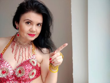 Kırmızı elbiseli bir dansçı beyaz arka planda doğulu bir dans ediyor. Metin için boş alan. Pankart. Profesyonel bir dansçı oryantal göbek dansı yapar. Kırmızı elbiseli seksi kadın baştan çıkarıcı danslar yapıyor.