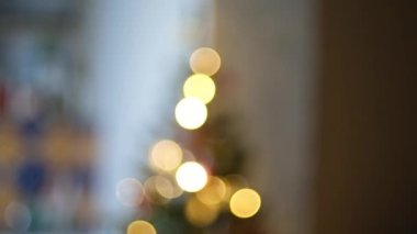 Happy New Year Christmas tree decorates with red glass ball on branch on background bokeh of side flickering light bulbs garlands for family holiday. Festival mood. Positive emotion