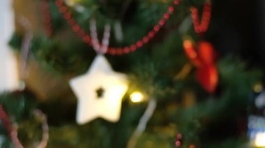 Happy New Year Christmas tree decorates with red glass ball on branch on background bokeh of side flickering light bulbs garlands for family holiday. Festival mood. Positive emotion