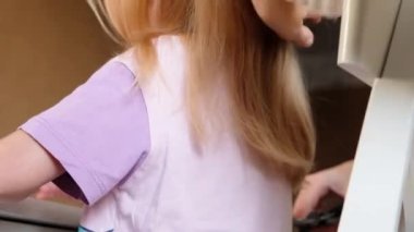Hairdresser Trimming the Ends of a Blond Girls Hair. Mother doing daughters haircut at home.