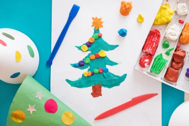 Making handmade Christmas cards. Childrens DIY concept. Little girl doing Christmas tree decoration or greeting cards from plasticine. Crafts for children