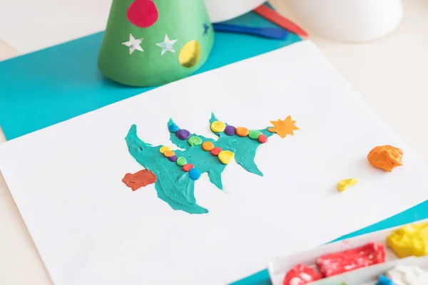 Making handmade Christmas cards. Childrens DIY concept. Little girl doing Christmas tree decoration or greeting cards from plasticine. Crafts for children