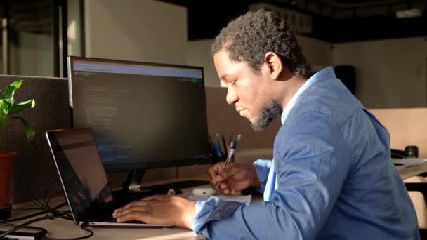 Black Man Writing Lines Code Desktop Two Monitors Laptop Aside — Stock Video
