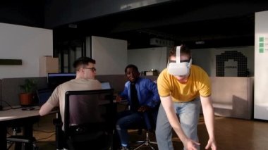 Bilgi İşlem Geliştirme Ekibi VR Projesi üzerinde çalışıyor. VR kulaklık takan, sanal dünyada bir şeylere dokunan ve çalan bir adam. Video oyunu yaratmak için VR teknolojileri ve bilgisayar kullanan çeşitli erkek programcılar 