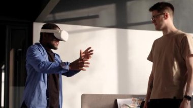 Bilgi İşlem Geliştirme Ekibi VR Projesi üzerinde çalışıyor. VR kulaklıklı bir adam metaevren dünyasını keşfediyor, sanal gerçeklik deneklerine dokunuyor. Ofiste soyut siber dünya.