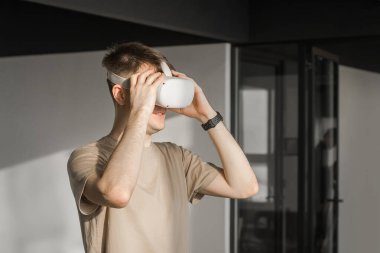 VR kulaklıklı bir adam metaevren dünyasını keşfediyor, sanal gerçeklik deneklerine dokunuyor. Ofiste soyut siber dünya.