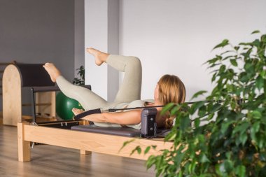 Kadın, ıslah yatağında pilates eğitiyor. Beden eğitimi için pilates stüdyosu makinesi. Formda, sağlıklı ve güçlü özgün bir vücut. Fitness konsepti. 