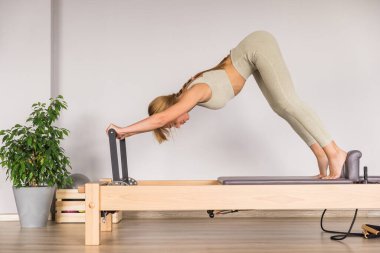 Kadın, ıslah yatağında pilates eğitiyor. Beden eğitimi için pilates stüdyosu makinesi. Formda, sağlıklı ve güçlü özgün bir vücut. Fitness konsepti. 