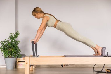 Kadın, ıslah yatağında pilates eğitiyor. Beden eğitimi için pilates stüdyosu makinesi. Formda, sağlıklı ve güçlü özgün bir vücut. Fitness konsepti. 
