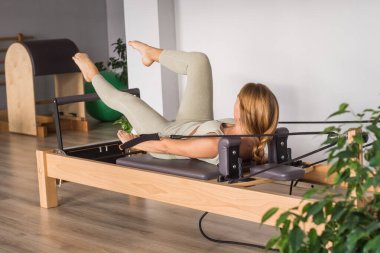 Kadın, ıslah yatağında pilates eğitiyor. Beden eğitimi için pilates stüdyosu makinesi. Formda, sağlıklı ve güçlü özgün bir vücut. Fitness konsepti. 
