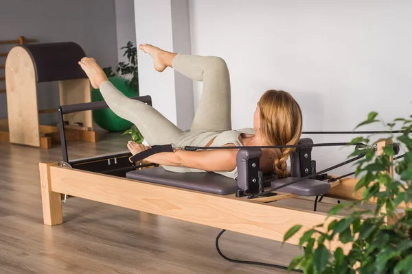 Kadın, ıslah yatağında pilates eğitiyor. Beden eğitimi için pilates stüdyosu makinesi. Formda, sağlıklı ve güçlü özgün bir vücut. Fitness konsepti. 