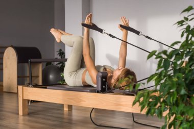 Kadın, ıslah yatağında pilates eğitiyor. Beden eğitimi için pilates stüdyosu makinesi. Formda, sağlıklı ve güçlü özgün bir vücut. Fitness konsepti. 