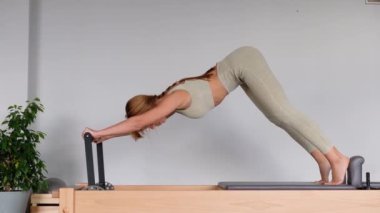 Kadın, ıslah yatağında pilates eğitiyor. Beden eğitimi için pilates stüdyosu makinesi. Formda, sağlıklı ve güçlü özgün bir vücut. Fitness konsepti. 