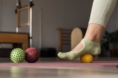 Antrenör turuncu spor lastiğiyle bacak esneme egzersizleri yapıyor. Pilates yoga stüdyosunda egzersiz yapan spor eğitmeni. Güzellik kavramı, vücut bakımı, sağlık. Kadın Sağlık Kulübü. 