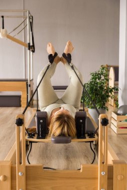 Kadın, ıslah yatağında pilates eğitiyor. Beden eğitimi için pilates stüdyosu makinesi. Formda, sağlıklı ve güçlü özgün bir vücut. Fitness konsepti. 