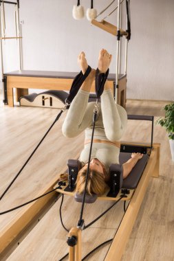 Kadın, ıslah yatağında pilates eğitiyor. Beden eğitimi için pilates stüdyosu makinesi. Formda, sağlıklı ve güçlü özgün bir vücut. Fitness konsepti. 