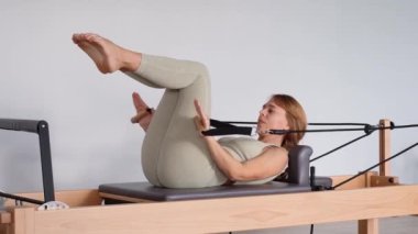 Kadın, ıslah yatağında pilates eğitiyor. Beden eğitimi için pilates stüdyosu makinesi. Formda, sağlıklı ve güçlü özgün bir vücut. Fitness konsepti. 