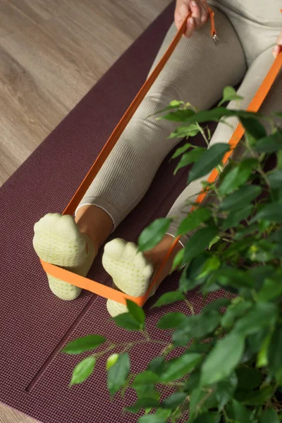 stock image Trainer doing leg stretching exercises with orange fitness rubber bands. Fitness trainer doing exercises in pilates yoga studio. Concept of beauty, body care, health. Women health club. 