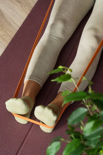 stock image Trainer doing leg stretching exercises with orange fitness rubber bands. Fitness trainer doing exercises in pilates yoga studio. Concept of beauty, body care, health. Women health club. 