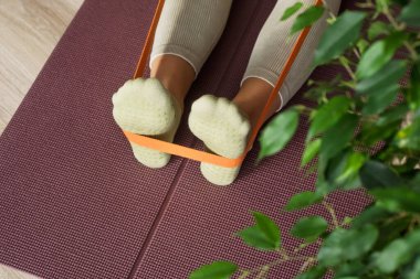 Antrenör turuncu spor lastiğiyle bacak esneme egzersizleri yapıyor. Pilates yoga stüdyosunda egzersiz yapan spor eğitmeni. Güzellik kavramı, vücut bakımı, sağlık. Kadın Sağlık Kulübü. 