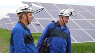 İki servis mühendisi ya da elektrikçi trafo alanını kontrol etmeye ve yeşil enerji güneş enerjisi santrali operasyonunun çözümünü bulmaya çalışıyor. Güneş Enerjisi Santrali 'nde teknisyen bakım güneş hücreleri.