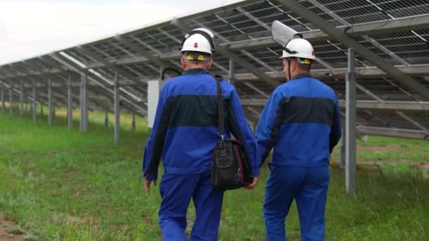 Dwóch Inżynierów Serwisowych Lub Elektryków Przechodzi Przez Panele Słoneczne Pracując — Wideo stockowe