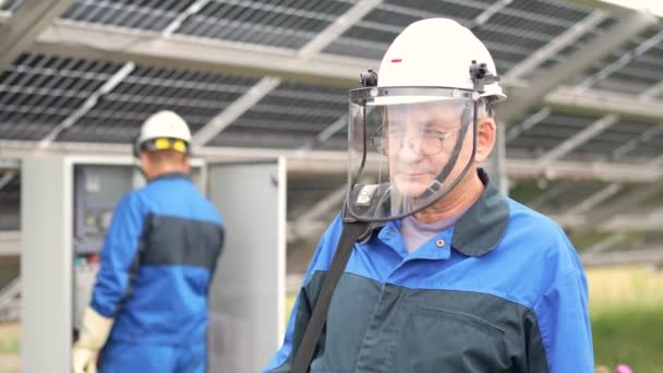 太陽電池パネルの前に立つ成熟したサービスエンジニアの男 技術者は太陽光発電所の太陽電池を朝の太陽光の下でメンテナンスする テクノロジー 太陽エネルギー再生可能エネルギー — ストック動画