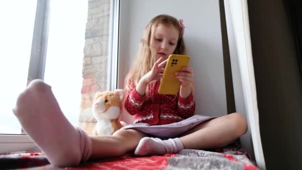 Petite Fille Jouant Téléphone Fenêtre Sur Une Couverture Fille Étreignant — Video