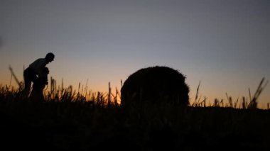 Anne ve kızı samanlıkla oynarken eğleniyor. Aile hafta sonu dışarıda, dışarıda. Sonbahar sezonu. Sonbahar hasadı.