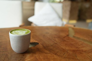 Ahşap masa arkaplanında latte kalp sanatı olan yeşil çay lattesinin üst görüntüsü..