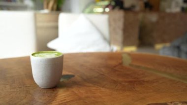 Ahşap masa arkaplanında latte kalp sanatı olan yeşil çay lattesinin üst görüntüsü..