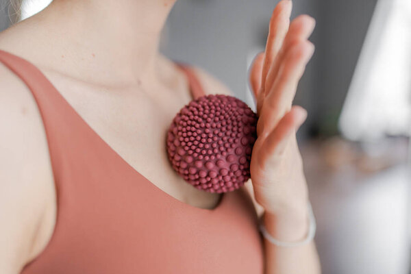 Тренер делает массажные движения на груди с фитнес резиновыми шариками. Тренер по фитнесу занимается в студии йоги пилатеса. Концепция красоты, ухода за телом, здоровья. Женский клуб здоровья