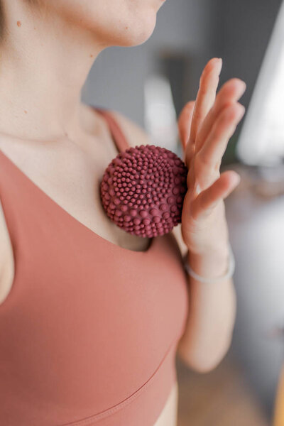 Тренер делает массажные движения на груди с фитнес резиновыми шариками. Тренер по фитнесу занимается в студии йоги пилатеса. Концепция красоты, ухода за телом, здоровья. Женский клуб здоровья