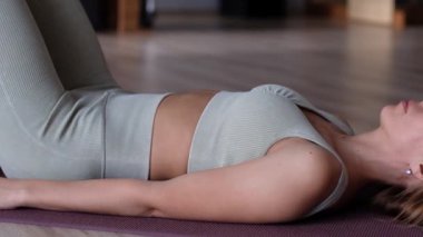 Genç sportif çekici kadınlar düzgün nefes alıyor karın kasları için egzersiz yapıyor, pilates yaparak karnını güçlendirmek için mekik çekiyor ve yoga stüdyosunda spor kıyafetleri giyiyor.. 