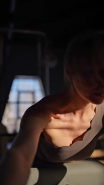 Aktif giyimli bir kadın güneşli bir stüdyoda göğüs ve sırt kasları için egzersiz yapıyor. Egzersiz yapmaya kendini adamış.