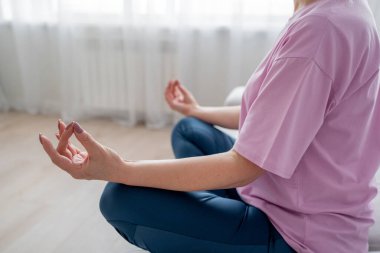 Son sınıf öğrencisi kadın bağdaş kurup yoga minderinde meditasyon yapıyor. Sakinlik ve rahatlığı kucaklıyor..