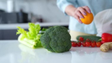 Bir kadın, yeniden kullanılabilir bir çantadaki taze sebzeleri modern bir mutfaktan çıkarır ve çevre dostu alışkanlıkları teşvik eder..