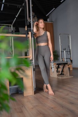 Pilates stüdyosunda spor eğitmeni. Yoga stüdyosunda spor kıyafeti giyen çekici genç bir kadın. Formda, sağlıklı ve güçlü özgün bir vücut. Fitness konsepti. 