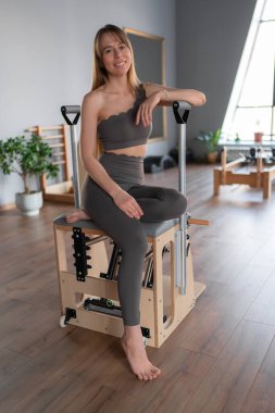 Pilates stüdyosunda spor eğitmeni. Yoga stüdyosunda spor kıyafeti giyen çekici genç bir kadın. Formda, sağlıklı ve güçlü özgün bir vücut. Fitness konsepti. 