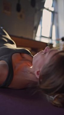 Reformist makinesinde çekirdek ve sırt kasları için pilates yapan kadın azimli ve güçlü vücut odaklı.