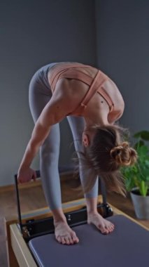 Reformist makinesinde çekirdek ve sırt kasları için pilates yapan kadın azimli ve güçlü vücut odaklı.